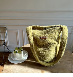 Nahaufnahme der flauschigen lindgrünen Plüsch-Tasche auf einem Holztisch im Alltag