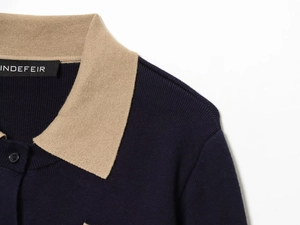 Close-up of contrast knit polo collar with beige panel and precise navy rib stitching