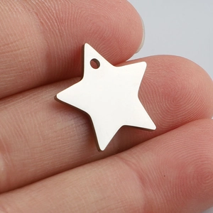 Macro view of silver star pendant on fingertip showing scale and polished metal finish