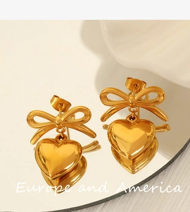 Macro detail of vintage gold bow and heart earrings with clear mirror reflection
