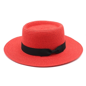 Detail of red boater straw hat featuring a wide flat brim and black ribbon bow accent