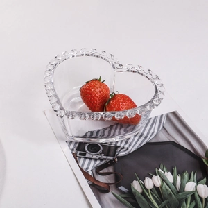 Close-up of heart-shaped glass bowl with beaded rim holding fresh red strawberries