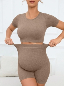 Detail showing the high elasticity and stretch of the brown ribbed maternity yoga shorts