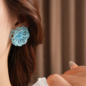 Close-up of blue beaded flower earrings worn by a model with elegant styling