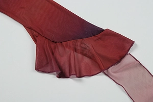 Détail du tissu en maille dégradé rouge avec volants et texture translucide