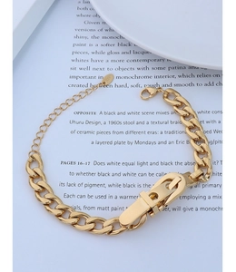Detail of 18k gold plated Cuban chain bracelet featuring K18 engraved tag on paper