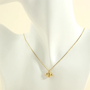 Detail view of 18K gold-plated bee pendant necklace shown on a mannequin bust