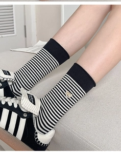 Detailansicht gestreifter Baumwollsocken in Schwarz-Weiß mit goldener Bärenbestickung