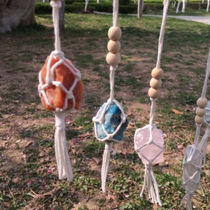 Detail of natural crystal stones in beige hand-woven macrame mesh bags with tassels