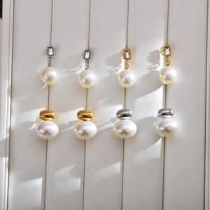 Close-up of elegant pearl stud earrings with crystal accents on a white leather tray