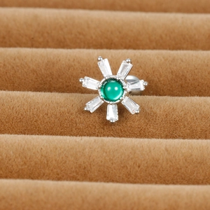 Macro shot of silver flower earring with green center gem and white zircon petals