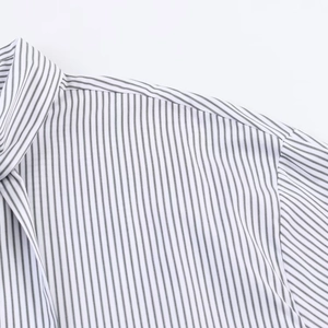 Dettaglio del colletto a rever e cucitura della spalla su una camicia di popeline a righe