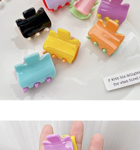 Close-up of candy-colored mini hair claws showing small size compared to fingers