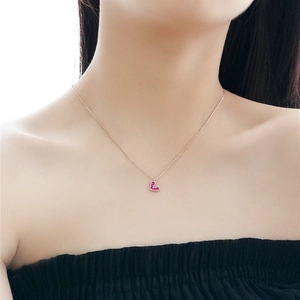 Detail of rose gold heart pendant necklace with pink gemstone on model neck