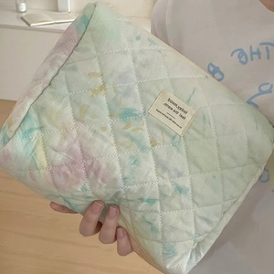 Close-up of quilted tie-dye makeup bag with mint and pink patterns and zipper detail