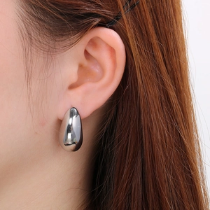 Macro close-up showing a silver teardrop earring on model with polished metal finish