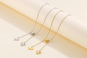 Détail de colliers or et argent avec curseur cœur et pendentifs libellule et papillon