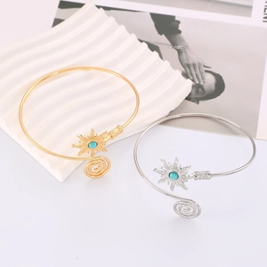 Detail of vintage gold and silver arm cuffs with turquoise sunflower pattern