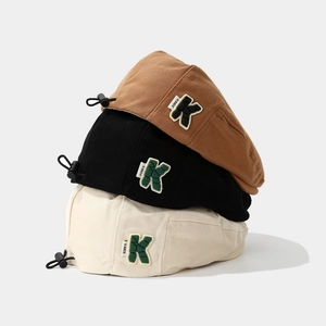 Detail of adjustable cord and K patch on corduroy berets in brown black and beige