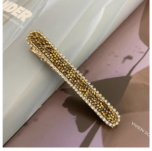 Close-up of sparkling rhinestone hair clip with bronze pyramid studs and metallic finish