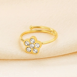 Macro detail of gold flower ring with zircon stones on beige silk background