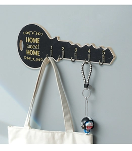 Detail of wooden key rack with gold Home Sweet Home text and five metal hooks
