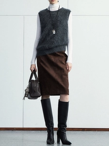 Detail of a grey faux fur vest paired with a brown slit skirt and high black boots