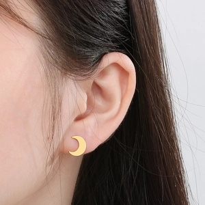 Close-up of a model wearing golden moon-shaped stud earrings in a minimalist style