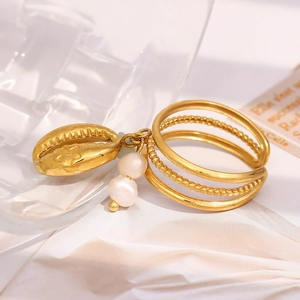 Detailed macro of 18K gold shell and pearl tiered ring on white fabric background