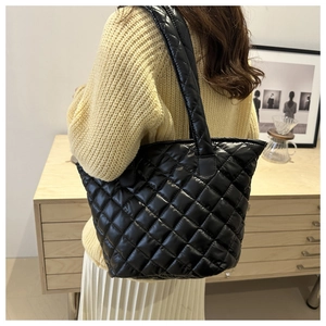 Detail view of the glossy quilted texture and spacious design of the black tote bag