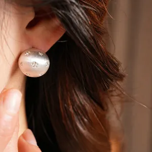 Boucles d'oreilles élégantes en argent brossé avec strass étoiles portées par le mannequin