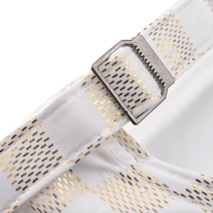 Macro shot of white satin fabric with gold dot patterns and a metal adjustment buckle