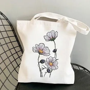 Minimalist wildflower garden canvas tote bag with purple cosmos print on a chair