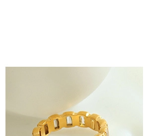 Gros plan sur une bague en acier titane doré ornée de cristaux rectangulaires transparents