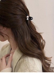 Détail d'une pince à cheveux noire élégante ornée de grandes perles sur modèle
