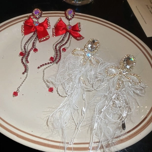Detail of red ribbon bow and white feather tassel earrings with sparkling crystals