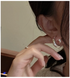 Gros plan de boucles d'oreilles créoles creuses minimalistes en argent S925 sur l'oreille