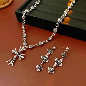 Detail of silver vintage cross pendant necklace and flower earrings set on leather