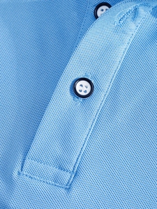 Gros plan du polo bleu ciel montrant la texture du tissu piqué et les boutons
