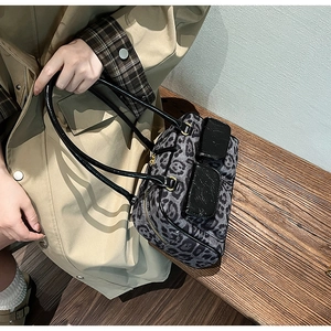 Detail of leopard print suede bowling bag featuring black patent leather handles and pockets