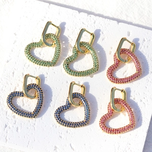 Tre paia di orecchini a cuore placcati oro 18K con zirconi verdi, rosa e blu su sfondo bianco