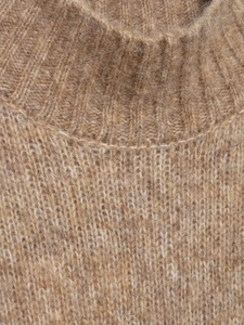 Macro shot of the ribbed neckline on a fluffy camel wool knit sleeveless vest