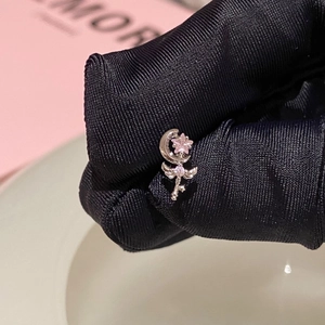 Macro shot of silver crescent moon earring with pink star gemstone and wing detail