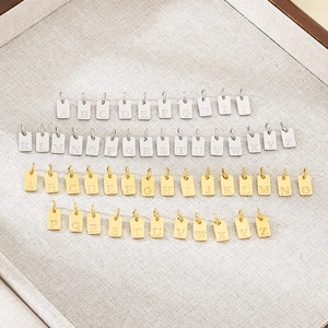 Macro detail of rectangular A-Z alphabet pendants in silver and gold stainless steel