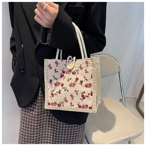 Close-up of floral canvas handbag with rose pattern, rope handles and wooden button