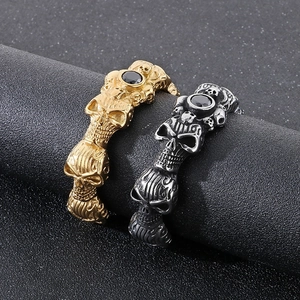 Gothic skull rings in gold and silver steel with black zircon stones on dark stand