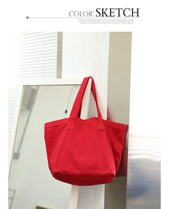 Detail of red canvas tote bag hanging on a white pillar in a minimalist indoor setting