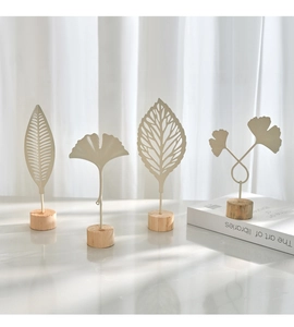 Detail of cream metal leaf sculptures on wooden bases with elegant window shadow lighting