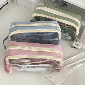 Detailed view of large capacity nylon pencil cases in pink, blue, and green on a desk