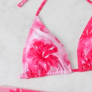 Detailed close-up of vibrant pink floral print halter bikini top on marble surface